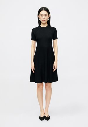 Sort kortærmet kjole med ribbet tekstur, tætsiddende liv og udvidet nederdel; har en rund halsudskæring og glat stof.