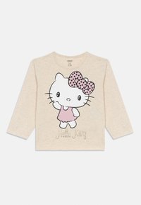 Hosszú ujjú bézs póló, nagy Hello Kitty grafikával, rózsaszín ruhában és pöttyös masnival. Az alján csillogó betűkkel "Hello Kitty" felirat található.