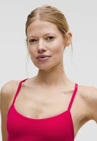 Jasnoróżowa bezrękawnik z cienkimi ramiączkami, charakteryzujący się gładką fakturą i dopasowanym krojem. Bez dodatkowych detali czy wzorów.