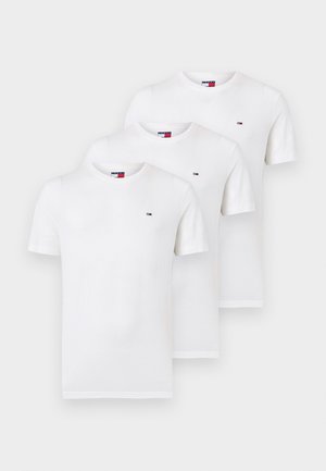 Tre magliette bianche semplici a maniche corte con scollo rotondo impilate, ciascuna con un piccolo logo Tommy Hilfiger sul petto a sinistra.