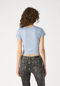 Svetle modré zkrácené tričko s krátkými rukávy, vyrobené z měkké látky. V kombinaci s tmavě šedými vybledlými skinny džíny s zadními kapsami.