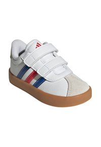 Zapato de cuero blanco con cinturones de velcro, con franjas rojas y azules. Suela de goma color canela y acento de ante beige en el área del dedo del pie.