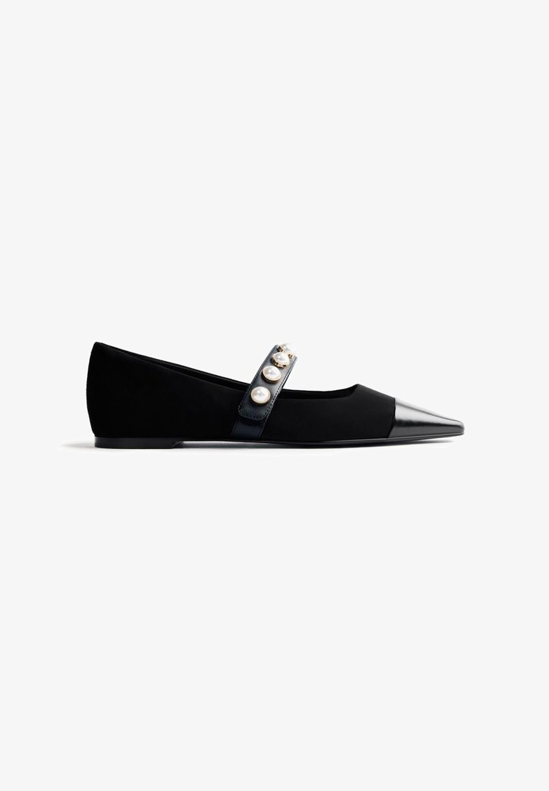 Chaussure plate noire avec un bout pointu brillant, dotée d'une bride sur le dessus ornée de quatre grosses perles fantaisie.