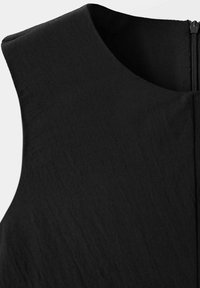 Robe noire sans manches avec col rond et fermeture éclair visible dans le dos, tissu texturé, vue rapprochée de la partie supérieure.