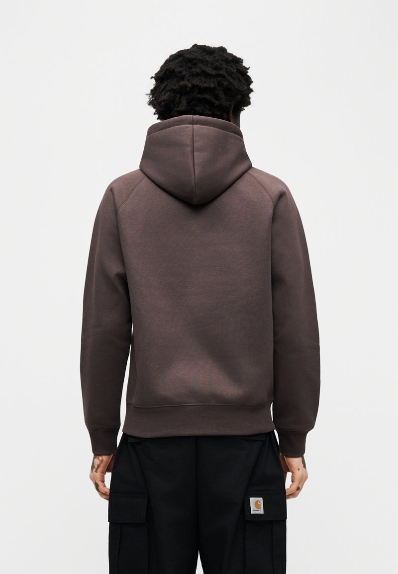 Brun hættetrøje med snøre i hætten, ribbede manchetter og kant. Stoffet har en glat tekstur og et minimalistisk design uden synlige logoer.