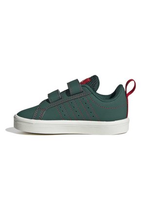 Sneaker verde scuro con cuciture rosse, due cinturini in Velcro, suola bianca e linguetta rossa sul tallone, mostrata di lato su sfondo bianco.