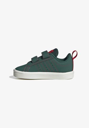 Baskets vert foncé avec surpiqûres rouges, deux bandes Velcro, semelle blanche et languette rouge au talon, vues de profil sur fond blanc.