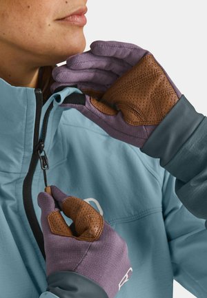 Purple gloves with brown textured accents, worn by a person adjusting a blue jacket's zipper, showcasing contrasting materials and colors.
