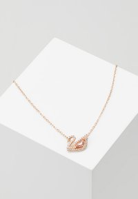 Rožu zelta kaklarota ar gulbja piekariņu, kas rotāts ar caurspīdīgajiem un rozā rhinestones, uz smalkas ķēdītes.