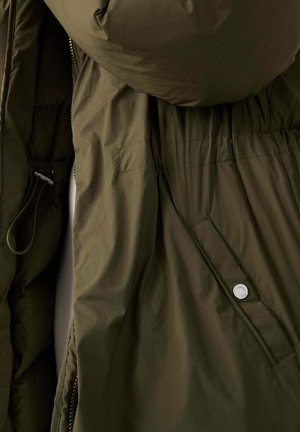 Giacca puffer verde oliva scuro con cappuccio, chiusura con zip, vita elasticizzata e dettagli con bottoni automatici sui lati. Tessuto morbido e liscio.