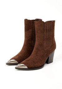 Bottines en cuir suédé marron avec talons empilés, panneaux latéraux élastiques et embouts en métal pointus avec des détails gravés.