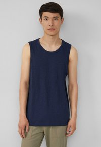 Marineblauwe mouwloze tanktop met een ronde halslijn, gemaakt van zacht materiaal. Heeft een subtiele logo op de borst en een relaxte pasvorm.