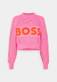 Růžový crop svetr s průsvitným vzorem a jednobarevnými rukávy. Velké oranžové logo "BOSS" na hrudníku. Texturovaná a lehká látka.