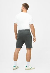 Gray cotton shorts with an elastic waistband and rear pocket, paired with a white t-shirt and white socks, worn with casual sneakers.