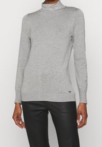 Szary sweter z wysokim kołnierzem, ozdobiony cyrkoniami, z prążkowymi mankietami i dołem, wykonany z miękkiego dzianinowego materiału.