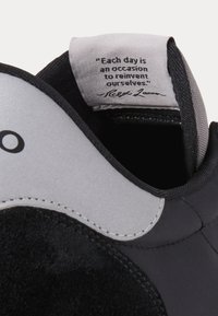 Černé tenisky s hladkým svrškem, semišovými akcenty a polstrovaným límcem. Mají prošívaný okraj a šedý jazyk s označením citátu uvnitř.