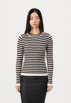 Maglione a righe bianche e nere a coste, con maniche lunghe e scollatura rotonda, abbinato a una gonna nera a tubino. Texture liscia.