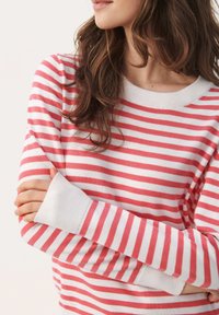 Stripet sweater med horisontale røde og hvide striber, ribbet strikstruktur, rund hals og forlængede ærmekanter.