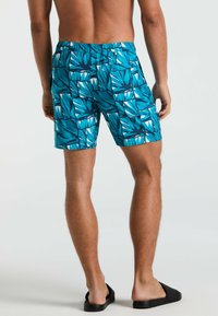 Un short de bain avec un motif géométrique de feuilles en teal et blanc, fabriqué en tissu léger. Il possède une taille élastique et des poches latérales.