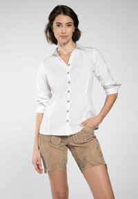 Witte overhemd met een gestructureerde kraag, decoratieve knopen en geborduurde manchetten, gecombineerd met bruine shorts met ingewikkelde patronen.