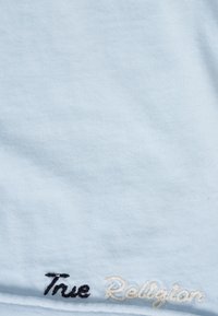 Hellblaues Baumwoll-T-Shirt mit schwarz-weiß besticktem "True Religion"-Schriftzug, strukturierter Stoff mit feiner Rippung.