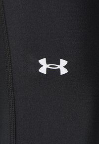 Pantalones deportivos negros con textura suave, con un logo blanco de Under Armour. Incluyen detalles de costura a lo largo de las costuras laterales.