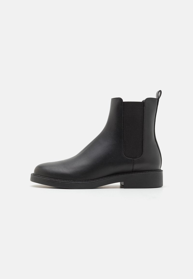 Botte Chelsea en cuir noir avec panneaux latéraux élastiques, languette au talon, petit talon bloc et bout arrondi, vue de côté extérieur.