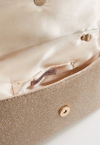 Zlatá metalická kabelka s texturovaným povrchem, hladkým saténovým podšívkou, bezpečným uzavřením na cvok a vnitřní štítkovou nálepkou.