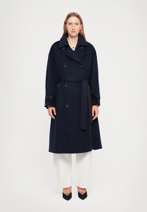 Trench coat doppiopetto blu navy con vita cinturata, realizzato in tessuto testurizzato, caratterizzato da grandi bottoni e tasche laterali.