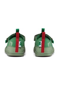 Scarpe verdi per bambini, realizzate in materiale morbido. Presentano una linguetta rossa sul tallone e un logo di ranocchia sul lato. Cinturino regolabile per una vestibilità sicura.