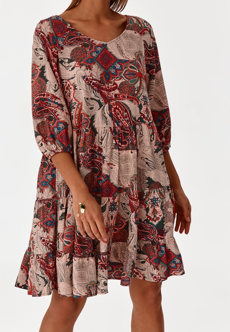 Robe à motif floral en tissu léger avec décolleté en V, manches trois-quarts et volants étagés à l'ourlet dans des tons terreux.