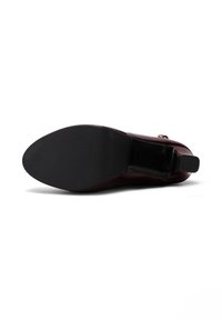 Scarpa con tacco alto color bordeaux, dalla finitura liscia e lucida, con una forma affusolata e suola in gomma nera testurizzata. Accento dorato sul tacco.