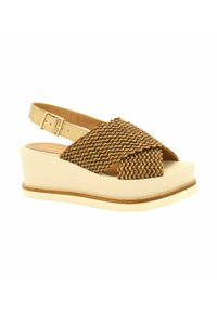 Sandalo con zeppa che presenta un design a strap intrecciata marrone con uno sfondo in pelle beige; suola piatta con un leggero accento marrone attorno alla base.