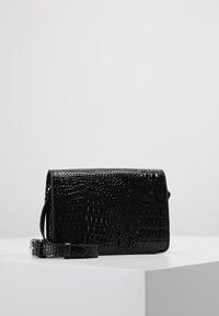 Borsa a tracolla nera realizzata in materiale lucido con motivo coccodrillo. Presenta una forma rettangolare e una tracolla rimovibile. Dettaglio della chiusura visibile.