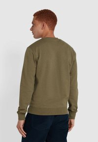 Groene sweatshirt met een ronde hals en geribde mouwen. De stof heeft een gladde textuur. gedragen met donkere broeken, gezien van achteren.