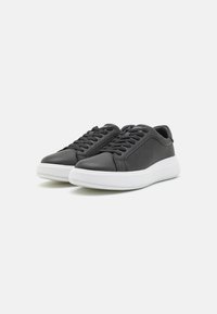 Black leather sneakers with a smooth finish, featuring a white rubber sole, rounded toe, and lace-up design, embossed pattern on the sides.