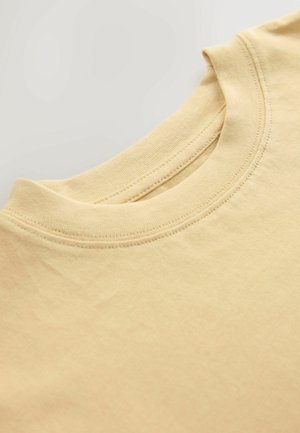 Šviesiai geltona medvilninė marškinėlė su apvalia iškirpte, turi ribotą apykaklę ir lygią tekstūrą. Audinys atrodo minkštas.