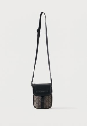 Mała prostokątna torba na ramię z czarną klapką, regulowanym paskiem i wzorzystym korpusem z powtarzającym się wzorem logo.