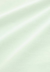Világos zöld textília sima felülettel; finoman fénylik és átlós redők vannak rajta, ami a puhaságot és rugalmasságot jelzi.