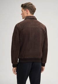 Bruine suede bomberjack met een geribbelde zoom en manchetten, slim fit en een klassieke kraag. Suède textuur zonder zichtbare versieringen.