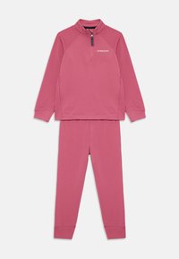 Ensemble deux pièces pour enfants avec un haut à manches longues zippé et un pantalon assorti en rose pâle, comportant le logo de la marque sur la poitrine.