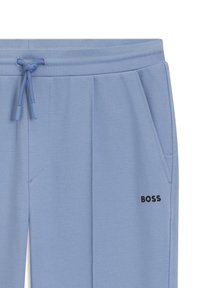 Svetlomodré nohavice so šnúrkou, bočnými vreckami, textúrovanou látkou a malým čiernym logom "BOSS" na pravej strane pri vrecku.