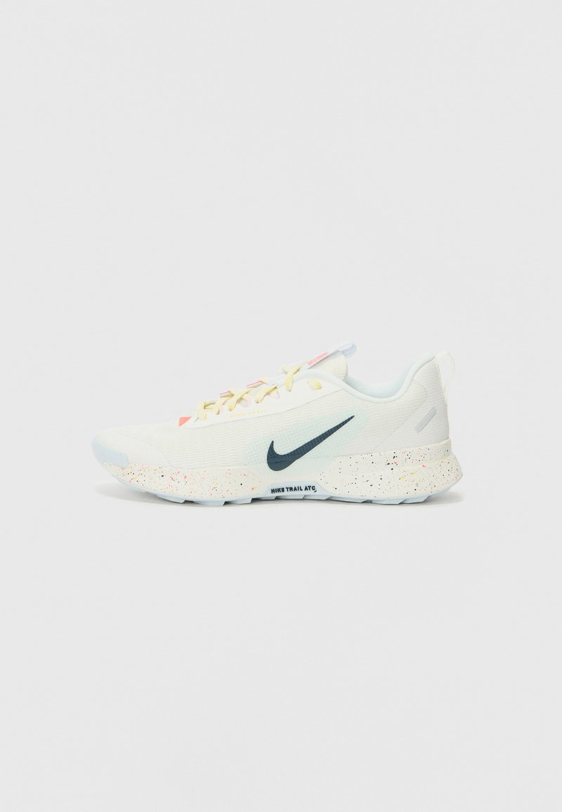 Nike trail running shoes in light cream with a textured mesh upper, a blue sole, and orange speckles on the midsole. Features white laces.