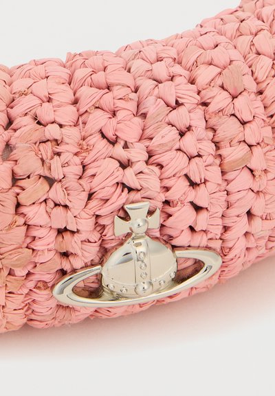 Κοντινό πλάνο ροζ υφασμάτινου υφάσματος με ασημένια σφαίρα και λογότυπο δακτυλίου που παρουσιάζει έναν σταυρό στην κορυφή.