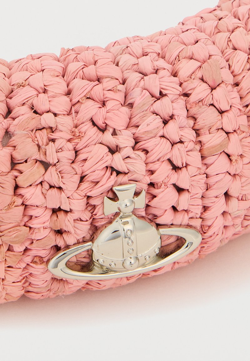 Primo piano di tessuto rosa intrecciato con un logo a forma di globo e anello argentati con una croce sulla sommità.