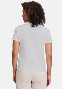 Hvid bomulds t-shirt med korte oprullede ærmer, rund halsudskæring og en afslappet pasform, båret med lyse bukser.
