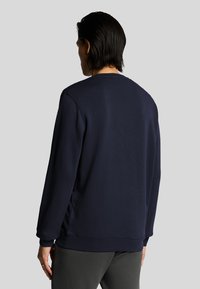Felpa blu navy con scollatura rotonda, polsini a coste e vestibilità rilassata, caratterizzata da un tessuto liscio e dettagli laterali discreti.