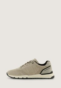 Zapatillas de malla beige con un upper texturizado, un sistema de lazada prominente, acentos negros y una suela de goma duradera.