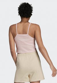 Top de tirantes finos de color rosa claro con canalé, combinado con pantalones cortos beige suaves con cintura elástica.