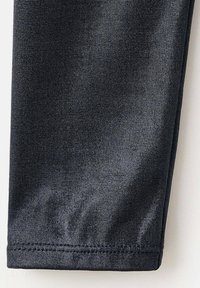 Čierne legíny z elastického materiálu, ktoré majú hladkú textúru, priliehavý strih a švy na spodnom okraji. Ideálne na bežné nosenie alebo športové aktivity.